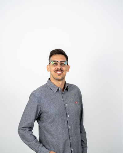 Mann mit Brille und grauem Hemd lächelt freundlich in die Kamera.